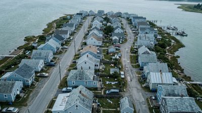 A coastal neighborhood of low houses seen from above, with water on two sides