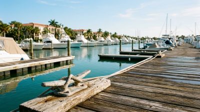 White pleasure boats moored in a calm Florida marina basin seen from a wooden dock